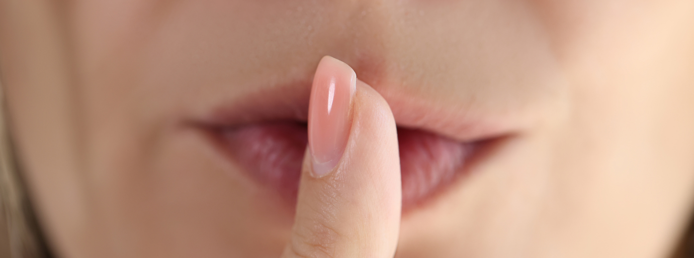 Eine Person, die einen Zeigefinger auf ihre Lippen legt