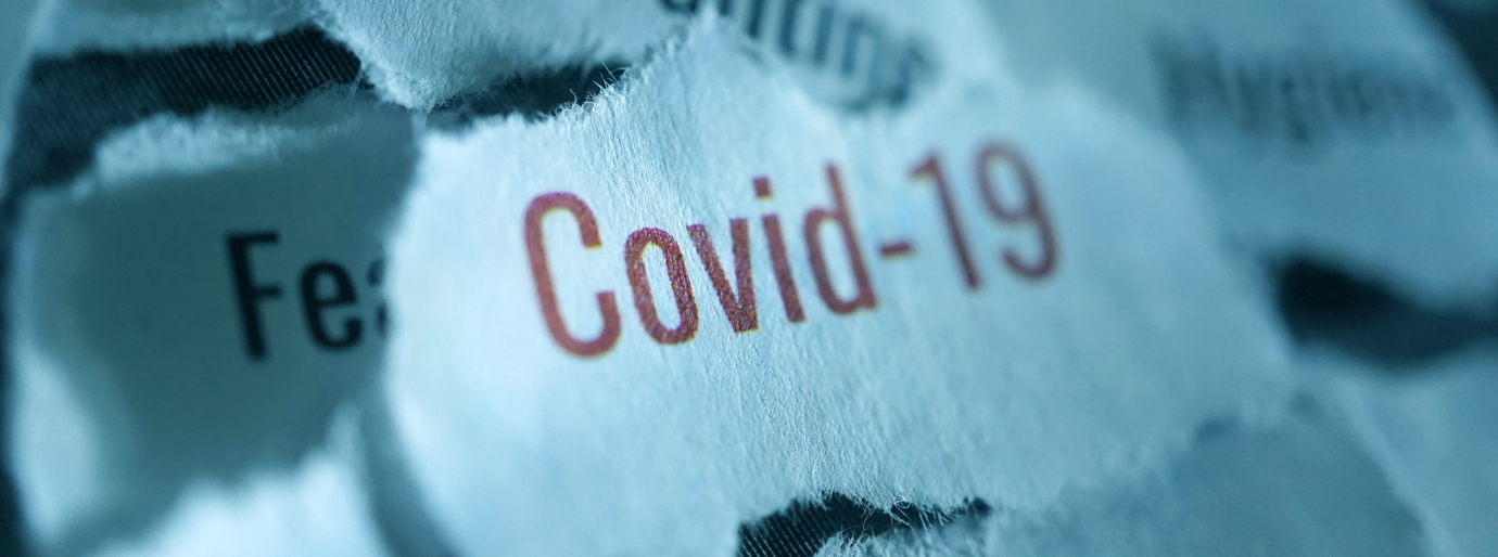Blaue Papierschnipsel, auf einem steht in rot "Covid 19"