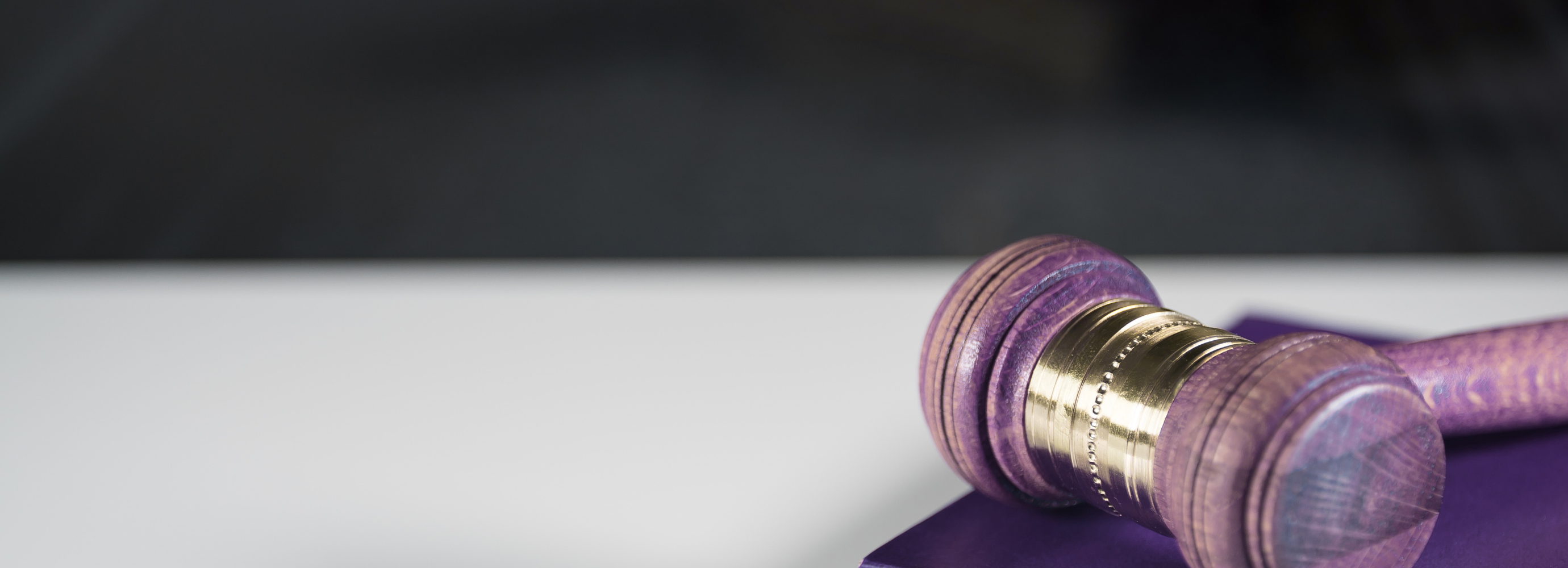 Ein Tisch, auf dem ein violettes Buch und ein Richterhammer liegt.