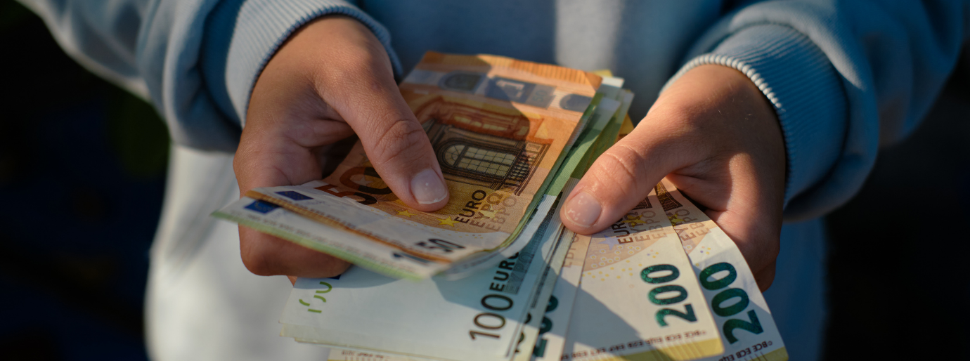 zwei Hände halten einen Fächer aus 50 €, 100 € und 200 € Scheinen